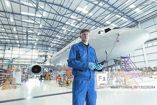 Portrait of apprentice aircraft maintenance engineer in maintenance hangar