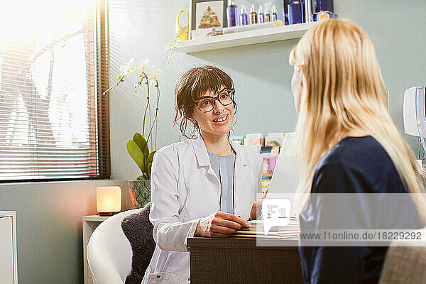 Beautician talking to patient at desk