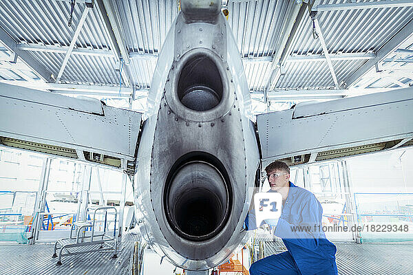 Apprentice aircraft maintenance engineer inspecting tail section of aircraft