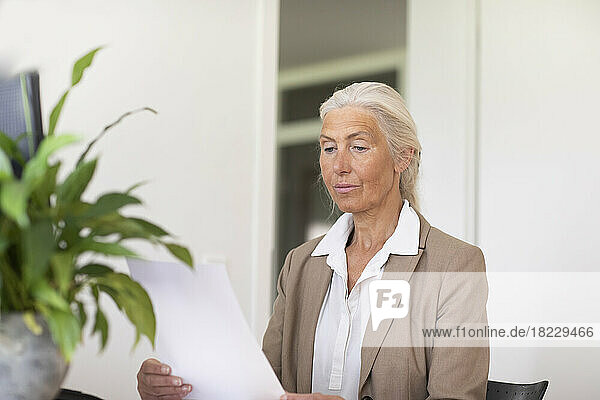 Mature businesswoman looking at document in office