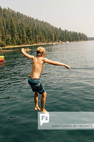 Boy (8-9) jumping into lake