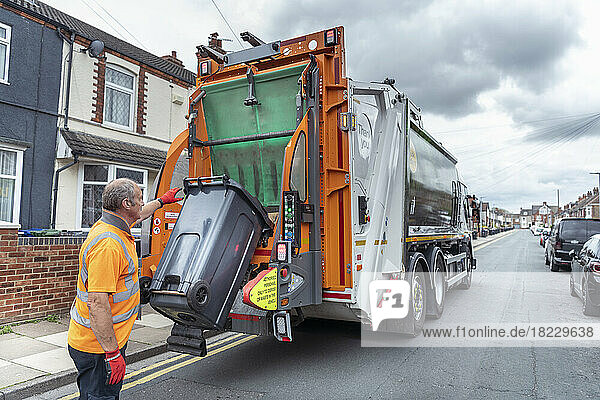 Refuse collector and refuse truck in street