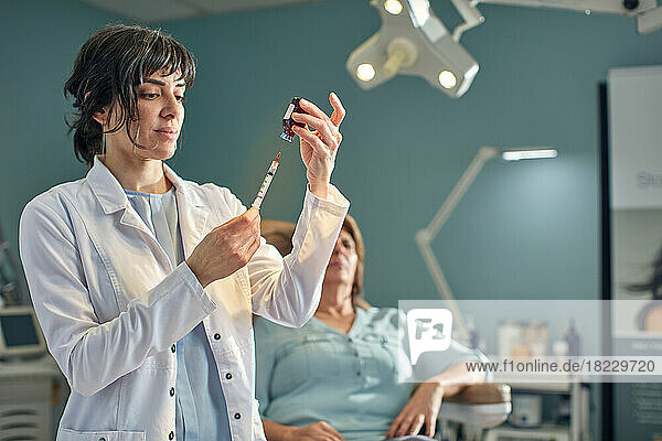 Female doctor preparing botox injection  patient in background