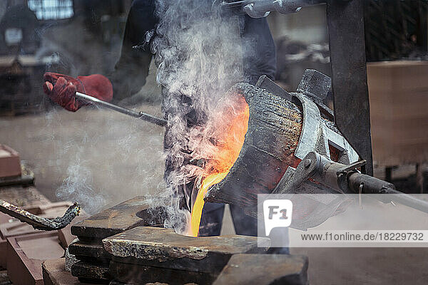 Worker pouring molten brass in brass foundry