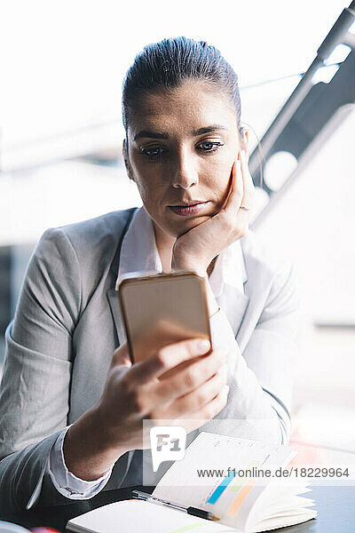 Junge Geschäftsfrau benutzt Smartphone im Café