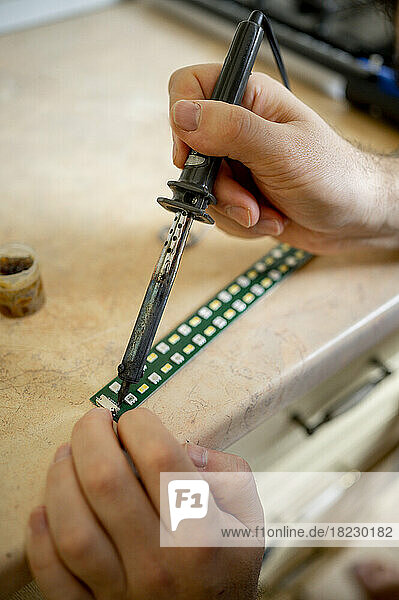 Hands of technician soldering circuit board at workshop