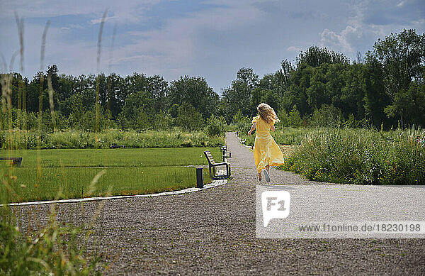 Carefree woman running on footpath in park