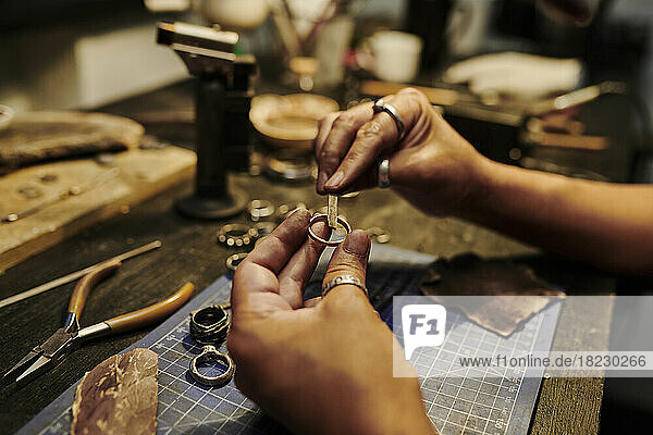 Hands of craftswoman repairing ring at workbench