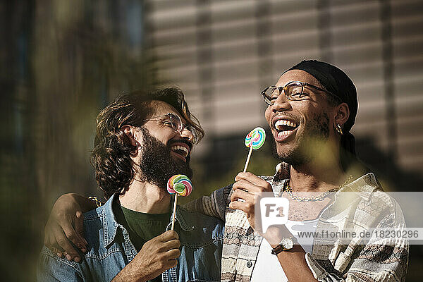 Happy gay couple eating rainbow candy