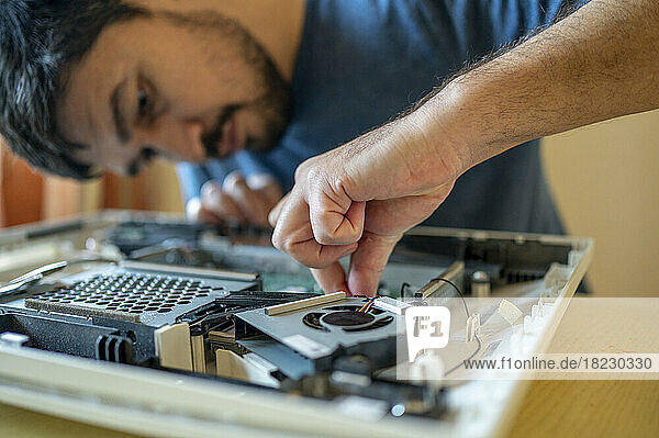 Man repairing mother board of computer on table at home