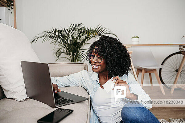 Happy businesswoman doing online shopping through credit card at home