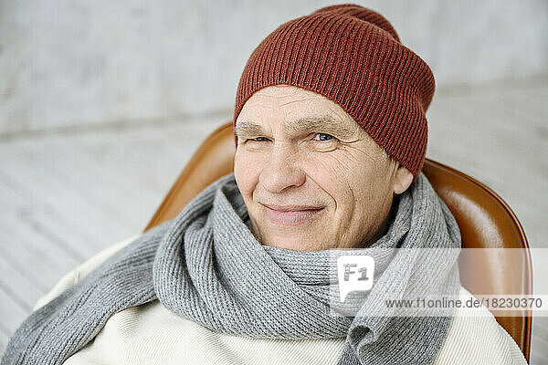 Smiling senior man wearing knit hat and scarf