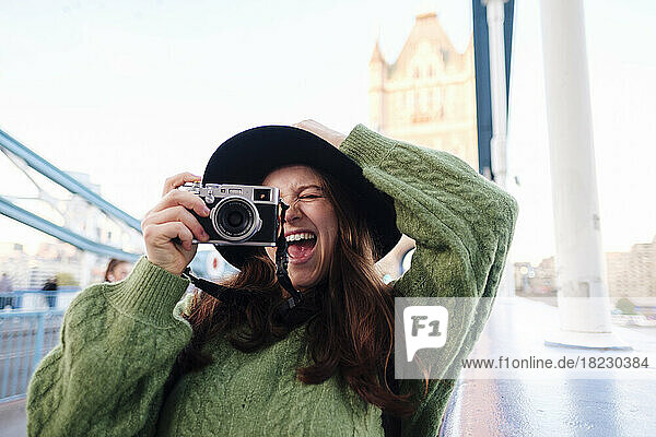 Glückliche junge Frau fotografiert mit der Kamera auf der Tower Bridge  London  England