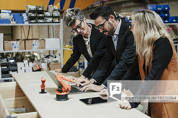 Happy businessman and businesswomen working on laptop at industry