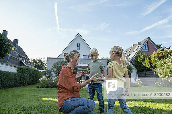 Happy mother playing with children in garden