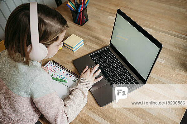 Girl studying through laptop on table