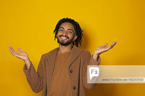 Happy man gesturing against yellow background
