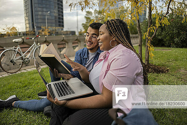 Happy young couple reading book together on grass