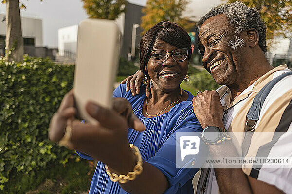 Happy senior couple taking selfie through smart phone at park