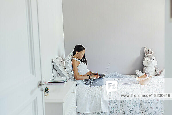 Girl using laptop and studying in bedroom