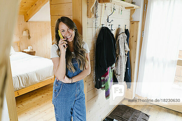 Happy young woman talking on smart phone in doorway