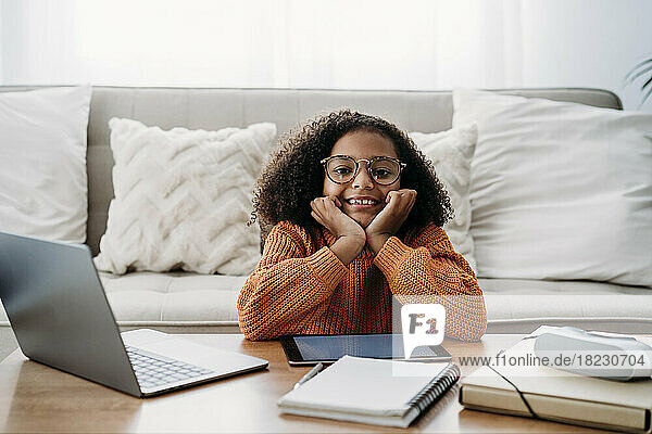 Happy girl wearing eyeglasses sitting in living room at home