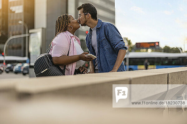 Junges Paar küsst sich vor dem Gebäude