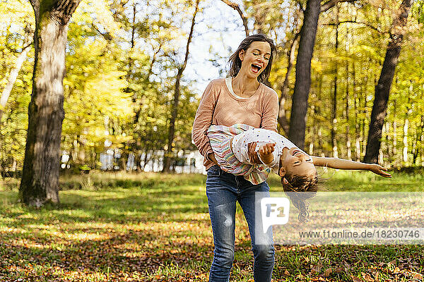 Playful mother carrying daughter in park