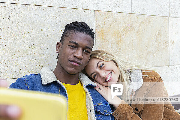 Smiling woman with man taking selfie through smart phone