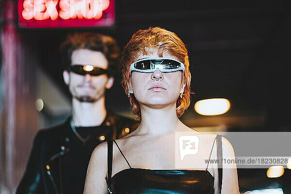 Young woman wearing smart glasses with boyfriend in background