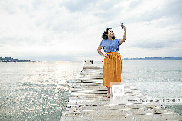 Woman taking selfie through smart phone standing on jetty
