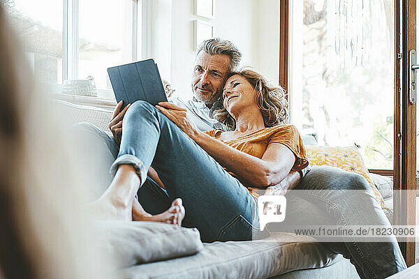 Loving mature couple using tablet computer on sofa in living room