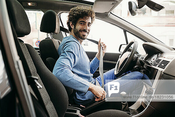 Smiling man wearing seat belt sitting in car
