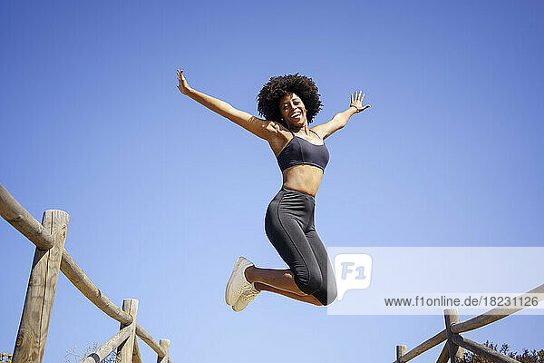 Cheerful woman jumping and having fun under blue sky
