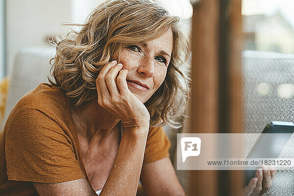Smiling woman with smart phone at home