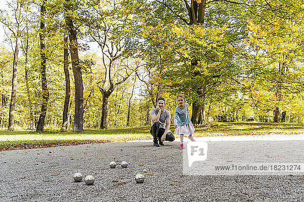 Girl playing boules with father in park