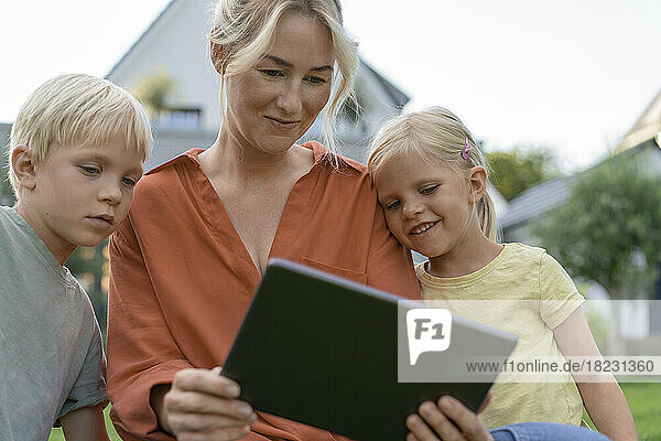 Smiling woman showing tablet PC to children