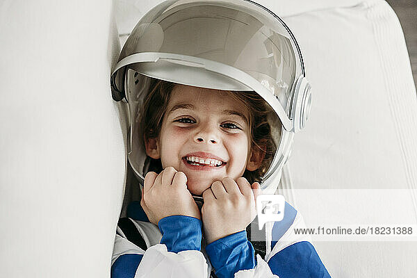 Happy girl wearing space costume lying on sofa