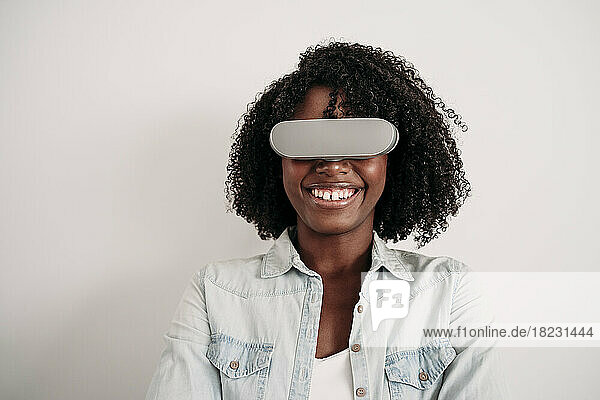 Happy young woman with curly hair wearing virtual reality headset