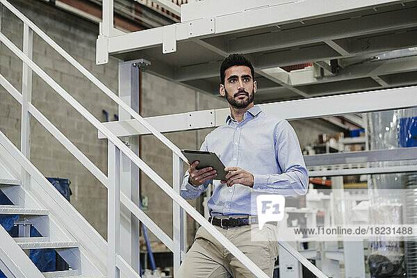 Nachdenklicher Geschäftsmann steht mit Tablet-PC auf der Treppe