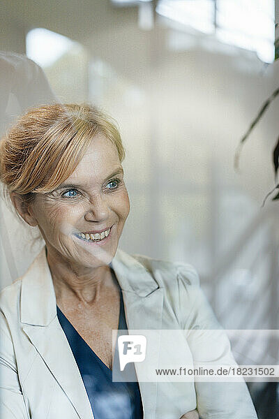 Happy businesswoman with blond hair seen through glass