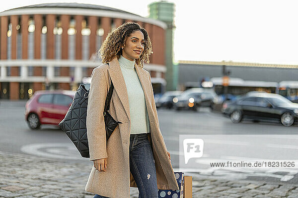 Junge Frau mit Einkaufstasche geht auf Fußweg