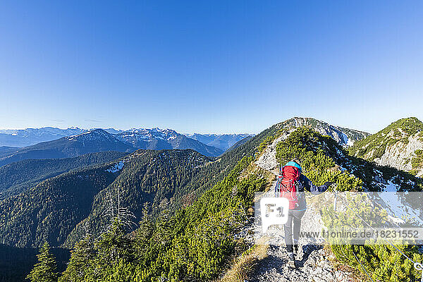 Germany  Bavaria  Female hiker following mountaintop trail in Bavarian Prealps