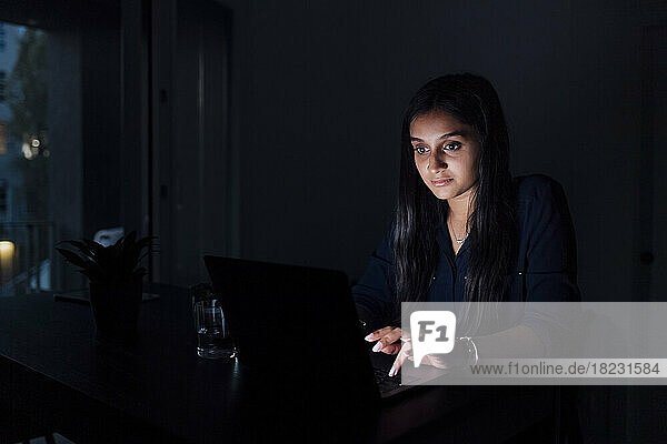 Young woman using laptop on table at home