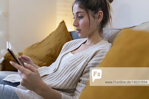 Smiling woman using tablet PC on sofa at home