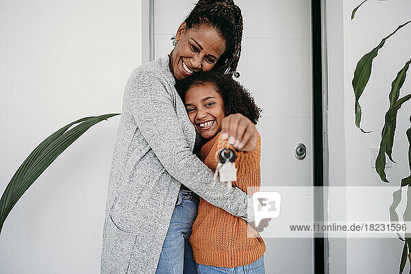 Happy mature woman hugging daughter showing house keys