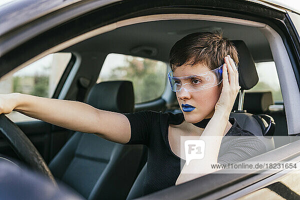 Woman with blue lipstick wearing smart glasses driving car