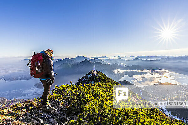Germany  Bavaria  Female hiker admiring surrounding landscape from summit of Herzogstand mountain