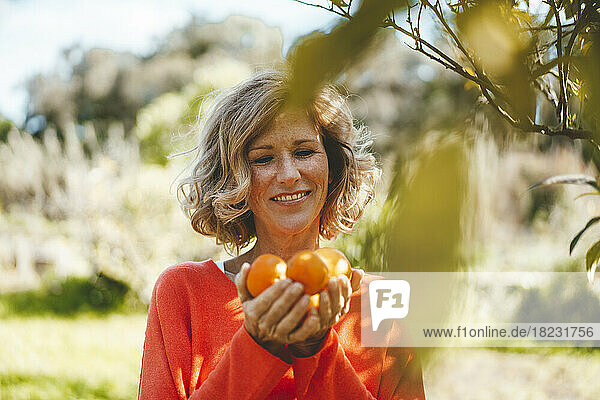 Happy woman holding fresh orange fruits