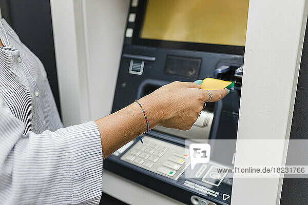Hand of woman inserting credit card in ATM machine
